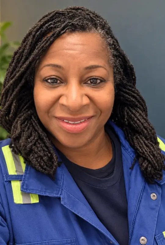 Sandra Williams, founder of SafeStart, smiling in blue hi-vis work coveralls